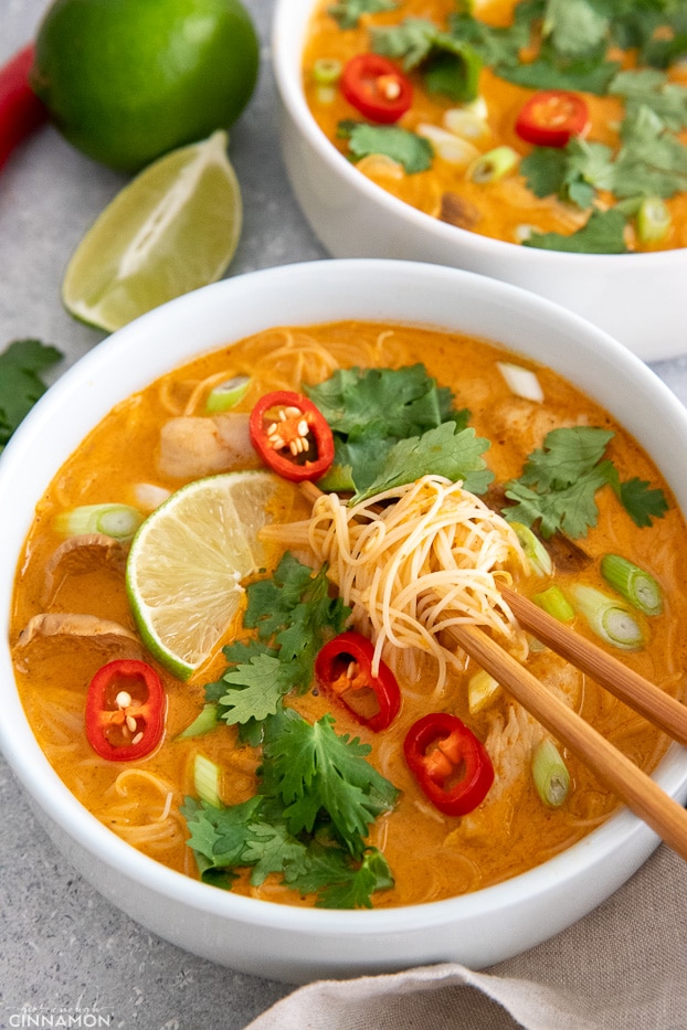 a bowl of Thai Coconut Curry Noodle Soup with chicken and rice vermicelli noodles with chopsticks in the soup bowl 